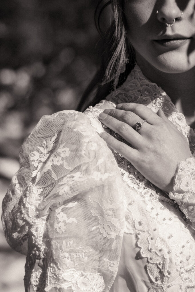 Cinematic photograph of an adventurous couple eloping in the forest, featuring the bride in a lace vintage wedding dress holding a floral bouquet while the groom is in a rustic suit. Captured by a destination wedding photographer in a documentary style.