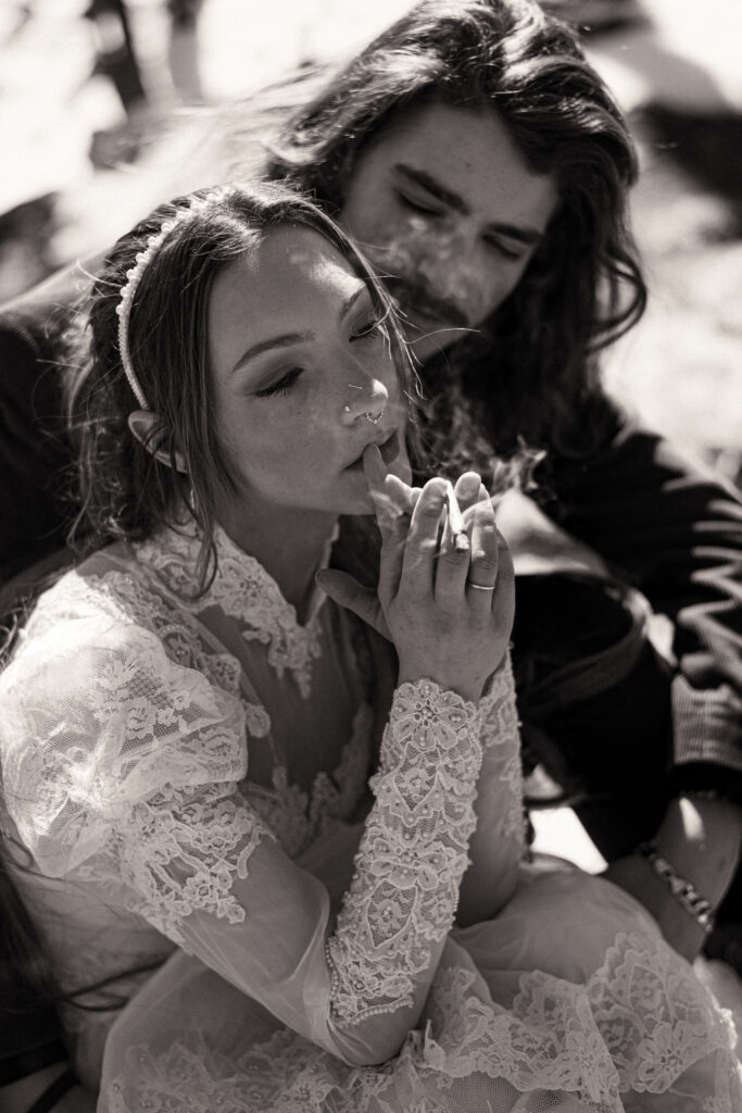 Cinematic photograph of an adventurous couple eloping in the forest, featuring the bride in a lace vintage wedding dress holding a floral bouquet while the groom is in a rustic suit. Captured by a destination wedding photographer in a documentary style.