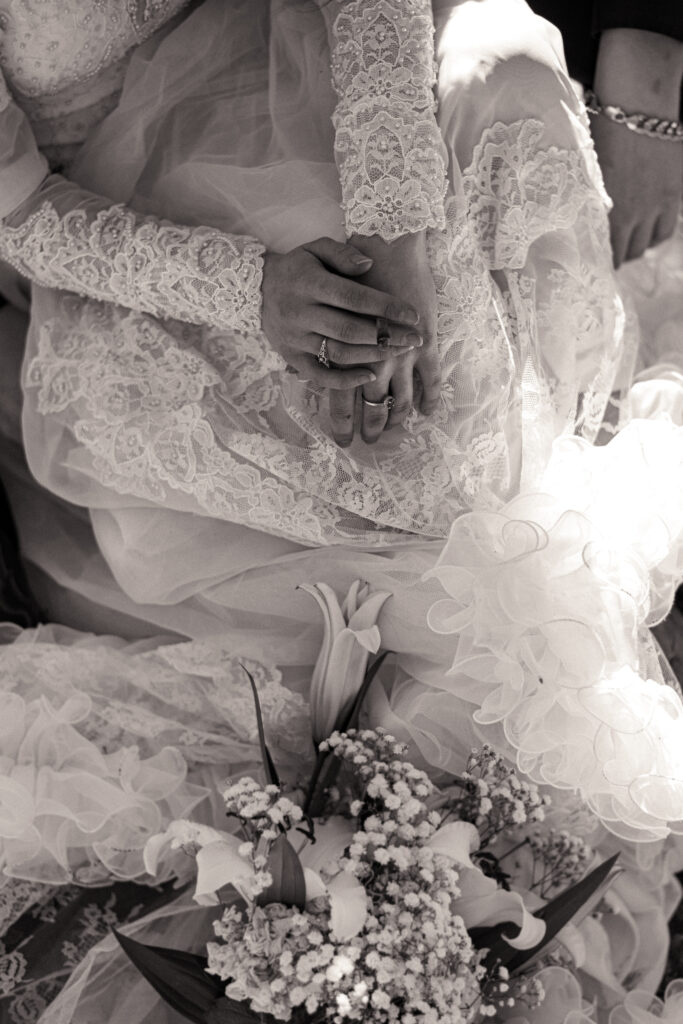 Cinematic photograph of an adventurous couple eloping in the forest, featuring the bride in a lace vintage wedding dress holding a floral bouquet while the groom is in a rustic suit. Captured by a destination wedding photographer in a documentary style.